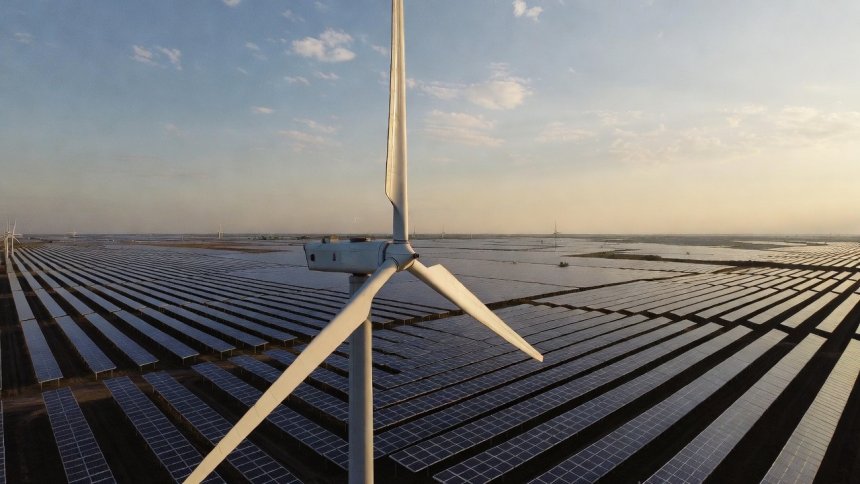 Ветренная турбина на фоне поля из солнечный панелей